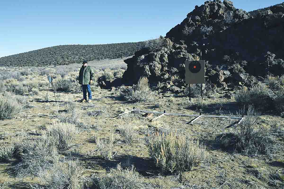 J.T. Parr is standing between the PVC bar with four microphones and the radio on a tripod. PVC extensions on the bar are stabilizers for microphone orientation. The target with the orange bullseye serves as an aiming point. This same target is used for a full day’s shooting without being replaced. The System 89 program records everything necessary, including group position and size.